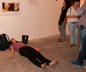 A performance artist lies in the middle of the floor, creating an obstacle