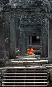 A saffron-robed Buddha statue in a temple gateway